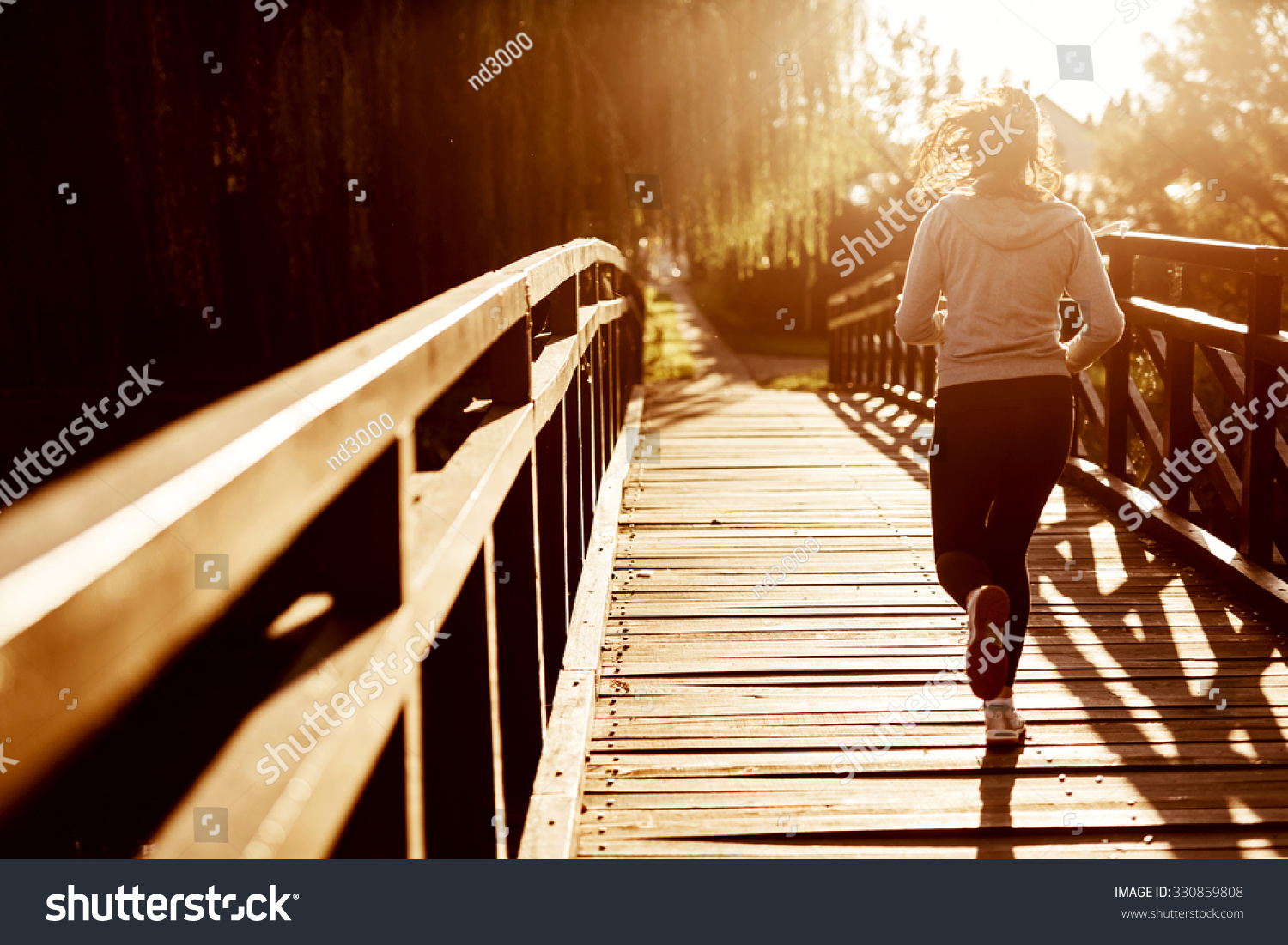 Beautiful female jogger running during sunset across bridge Beautiful female jogger running during sunset across bridge