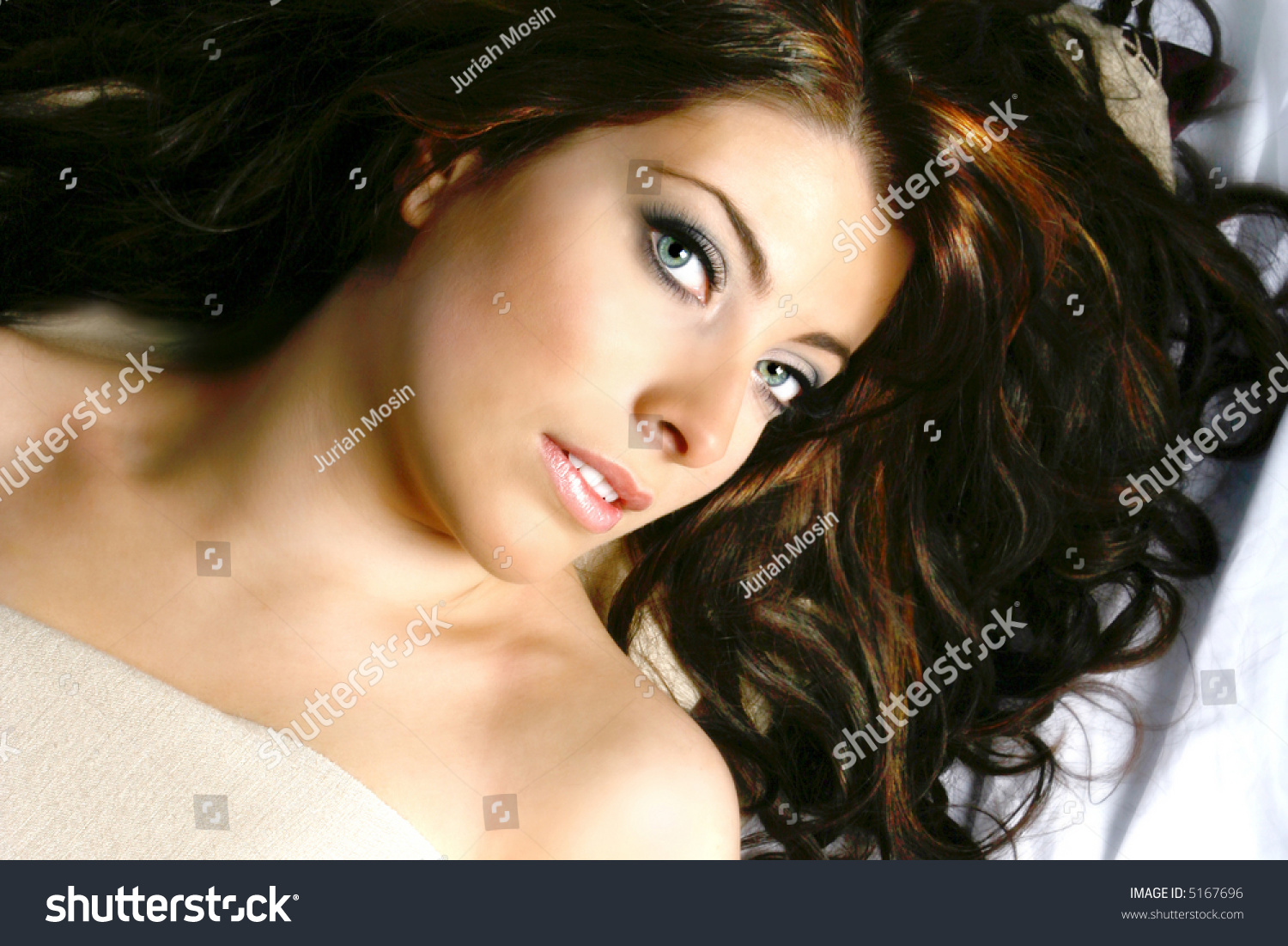 Beautiful Young Woman With Long Dark Hair Lying On Soft Bed Stock