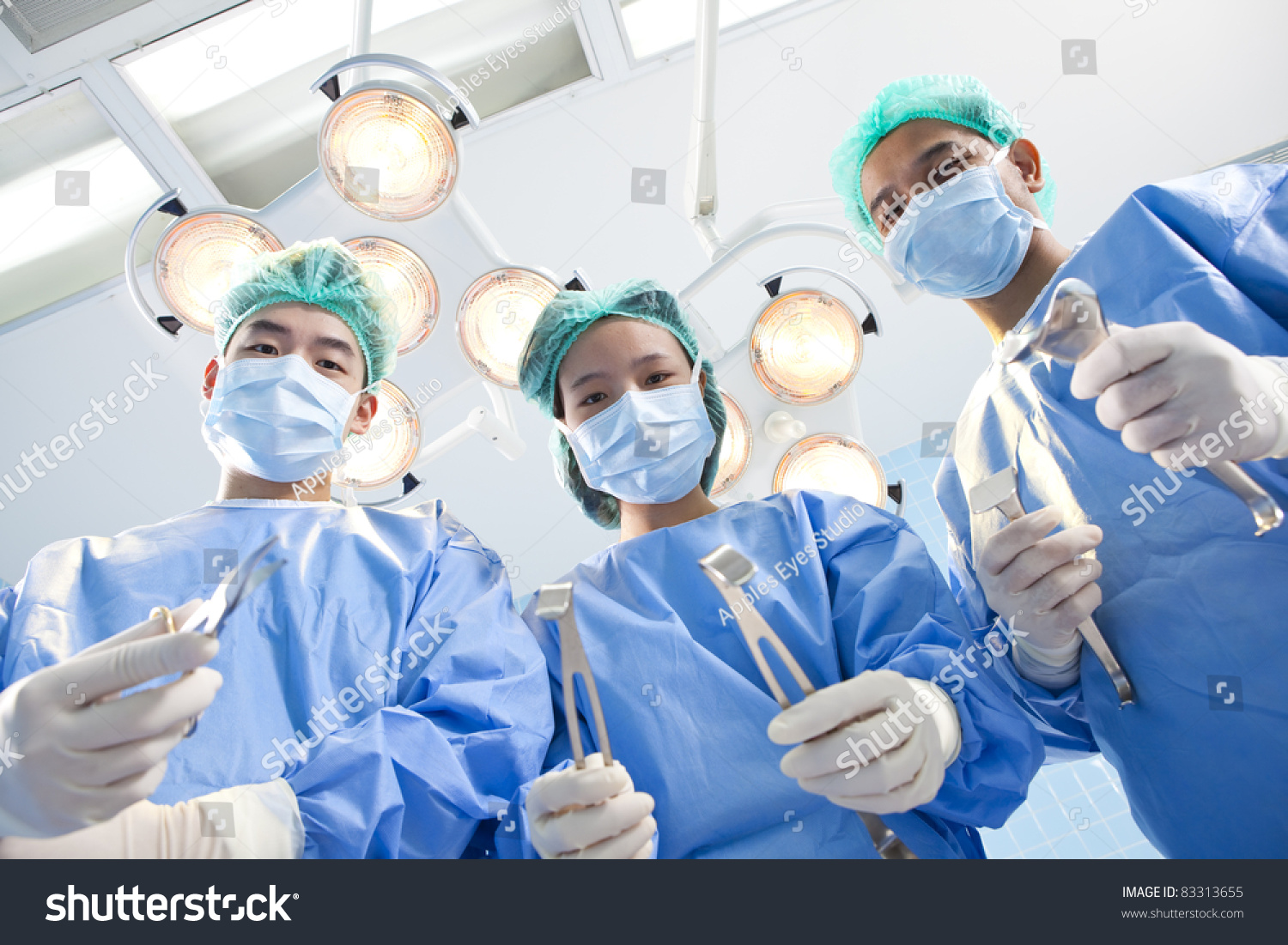 Below View Of Surgeons Holding Medical Instruments In Hands And Looking