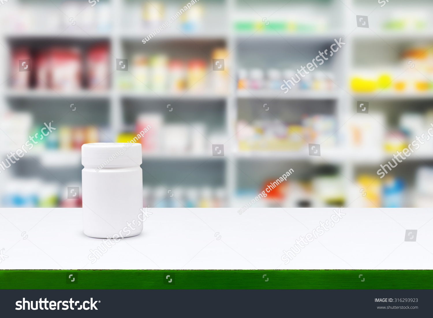 Blank white medicine bottle on counter with blur shelves of drug in the pharmacy drugstore background Blank white medicine bottle on counter with blur shelves of drug in the pharmacy drugstore background