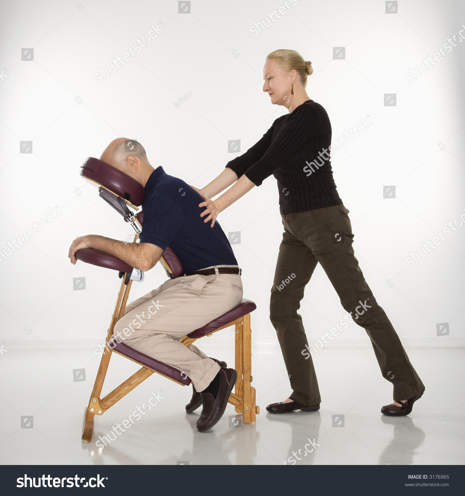 Caucasian Middle Aged Female Massage Therapist Massaging Back Of Caucasian Middle Aged Man