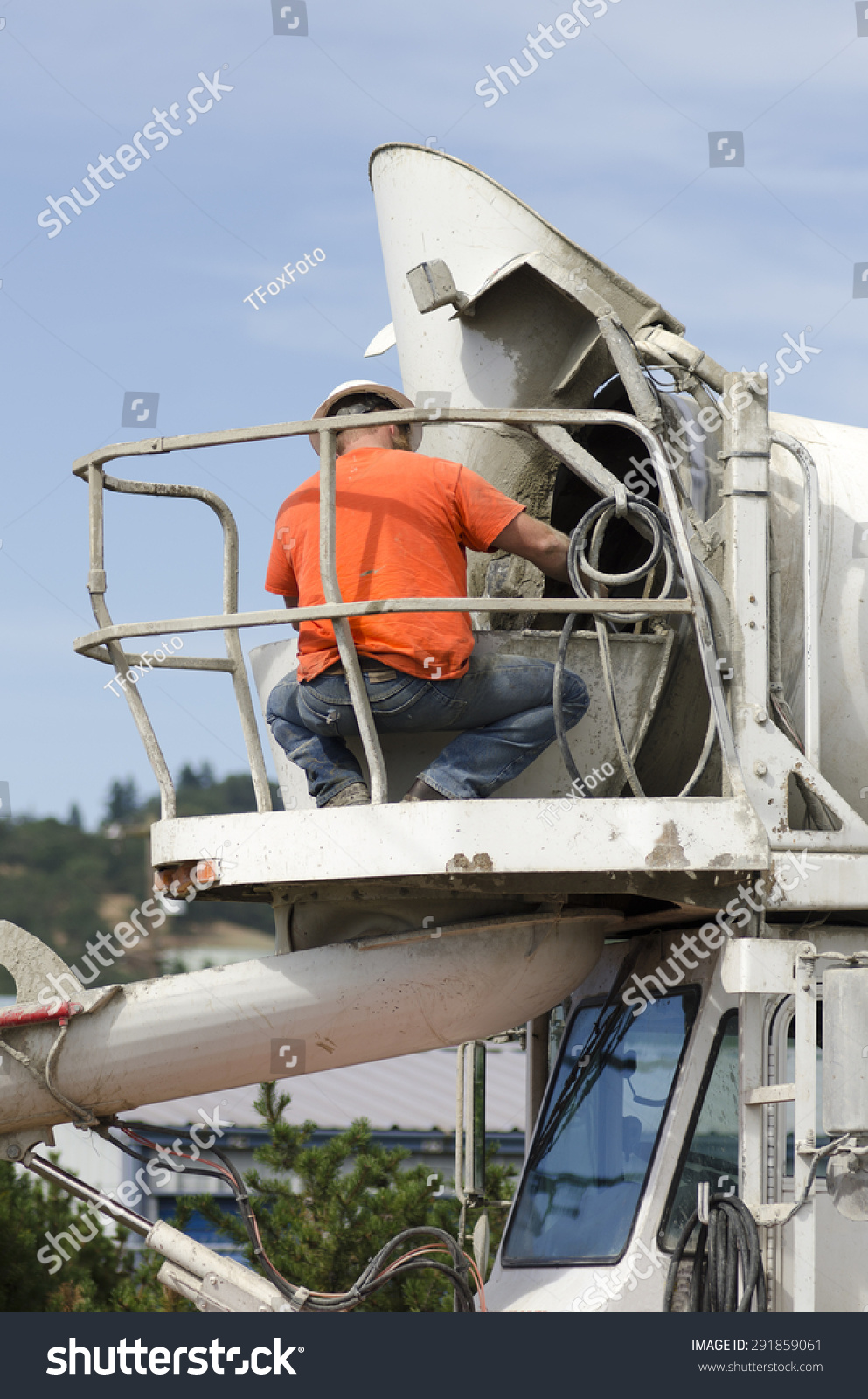 Cement Mixer Truck Driver Cleaning Up Concrete From Chute Following A
