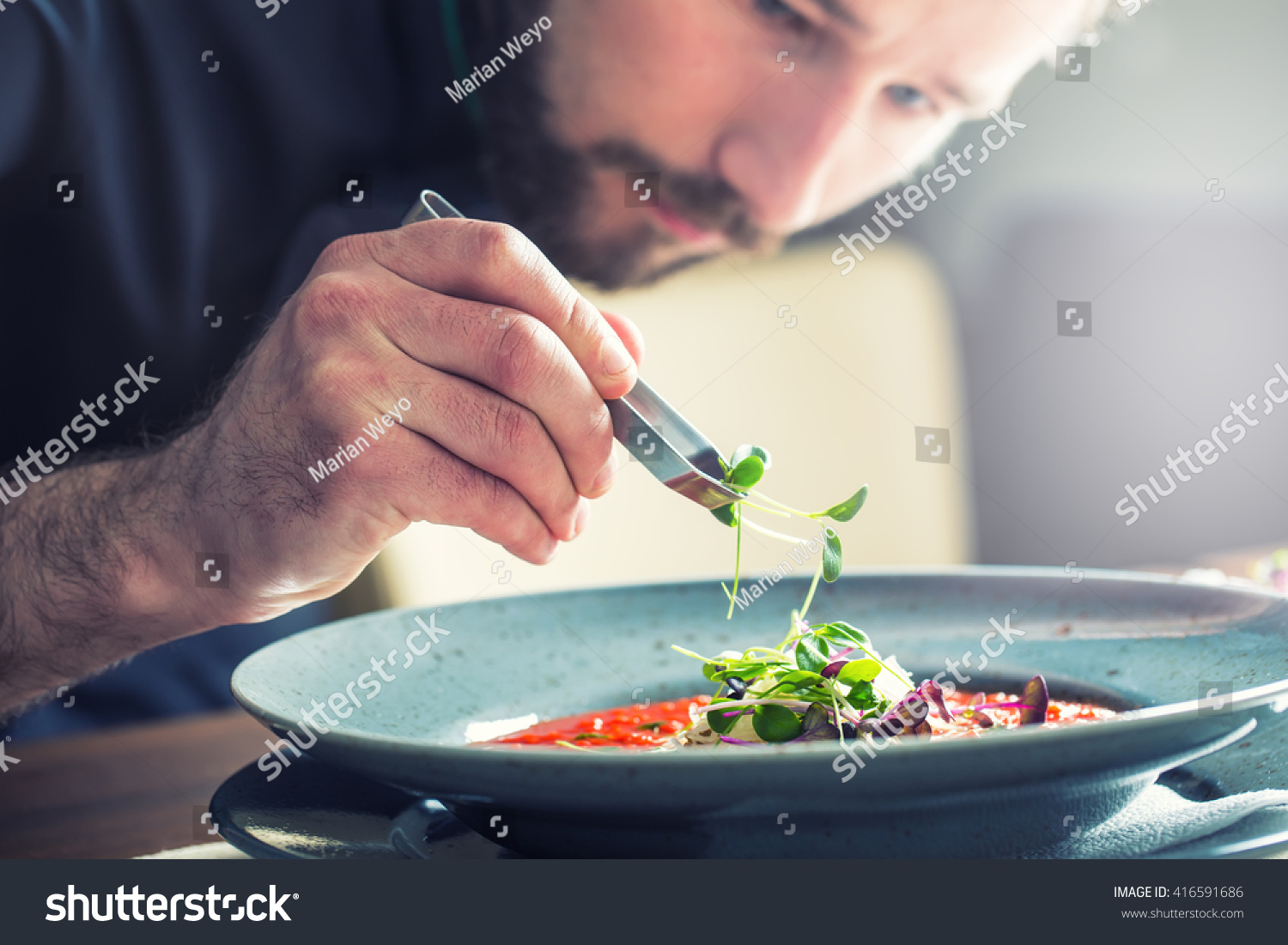 Chef in hotel or restaurant kitchen cooking, only hands. he is ...