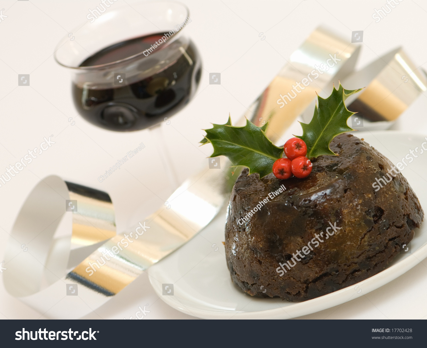 Christmas Pudding Decorated With Holly With A Glass Of Wine Stock Photo