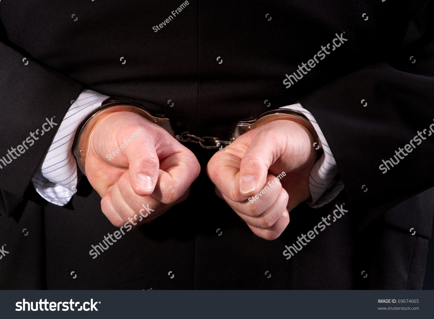 Close Up Of Man Wearing Suit Handcuffed Behind His Back Stock