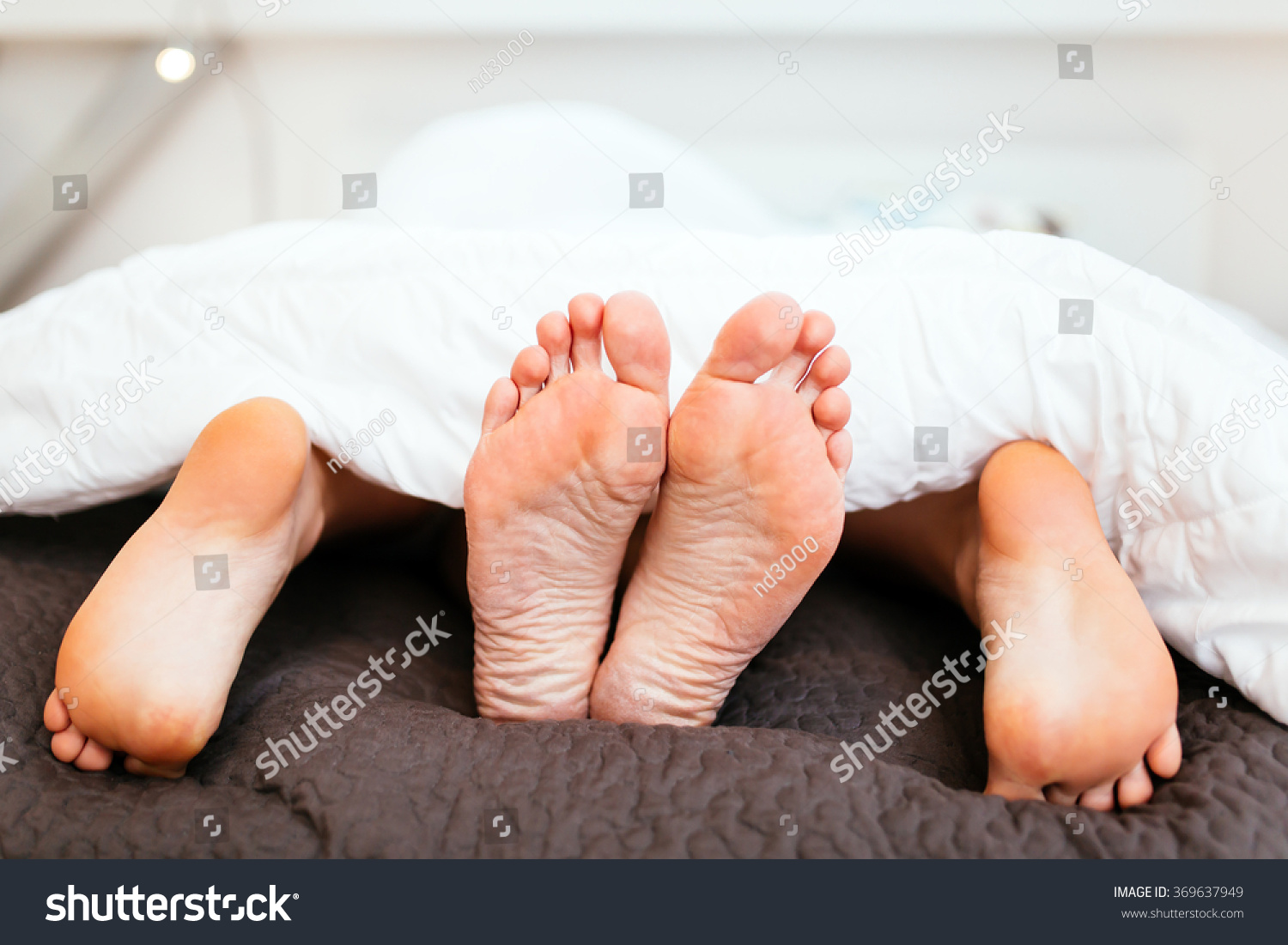 Couple Having Sex Under Blanket With Their Feet Visible Stock Photo