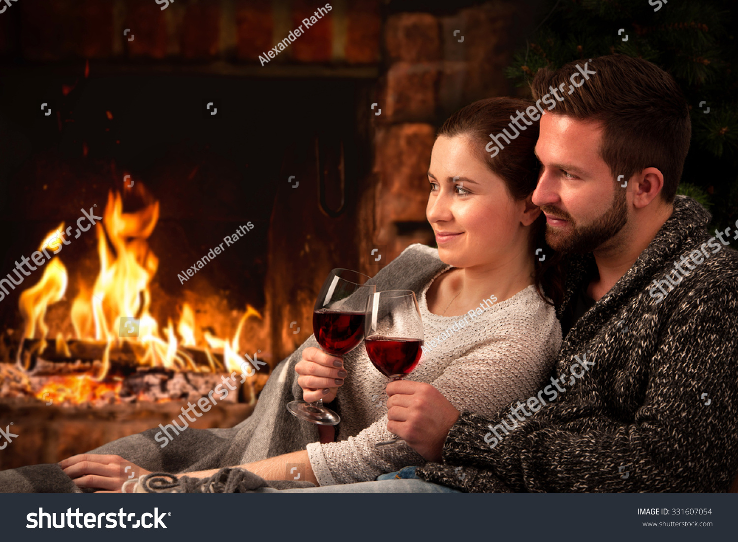 Couple Relaxing With Glass Of Wine At Romantic Fireplace On Winter Evening Stock Photo