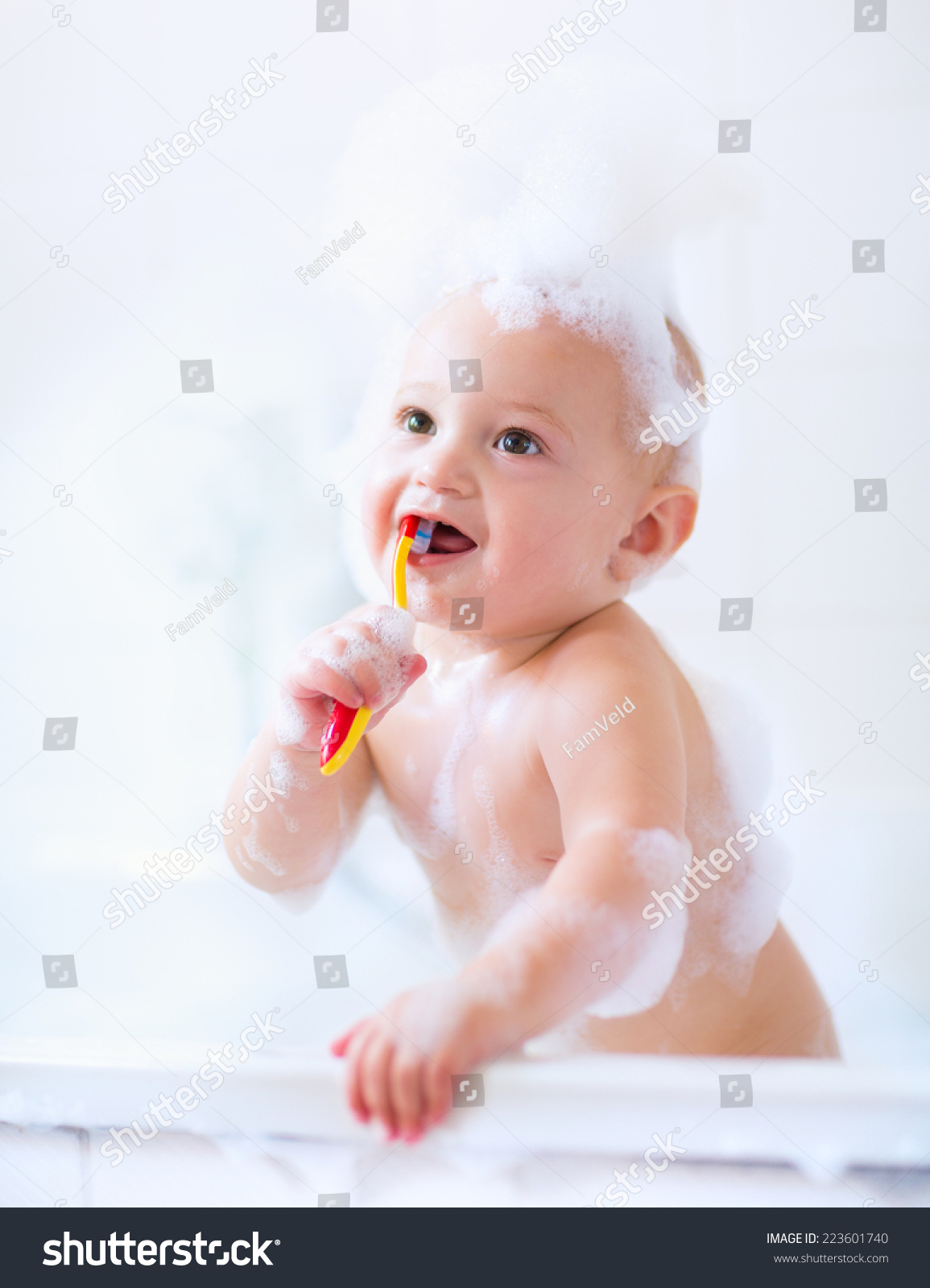 baby boy taking bath with foam brushing his teeth in a white bathroom stock baby boy taking bath with foam brushing his teeth in a white bathroom stock
