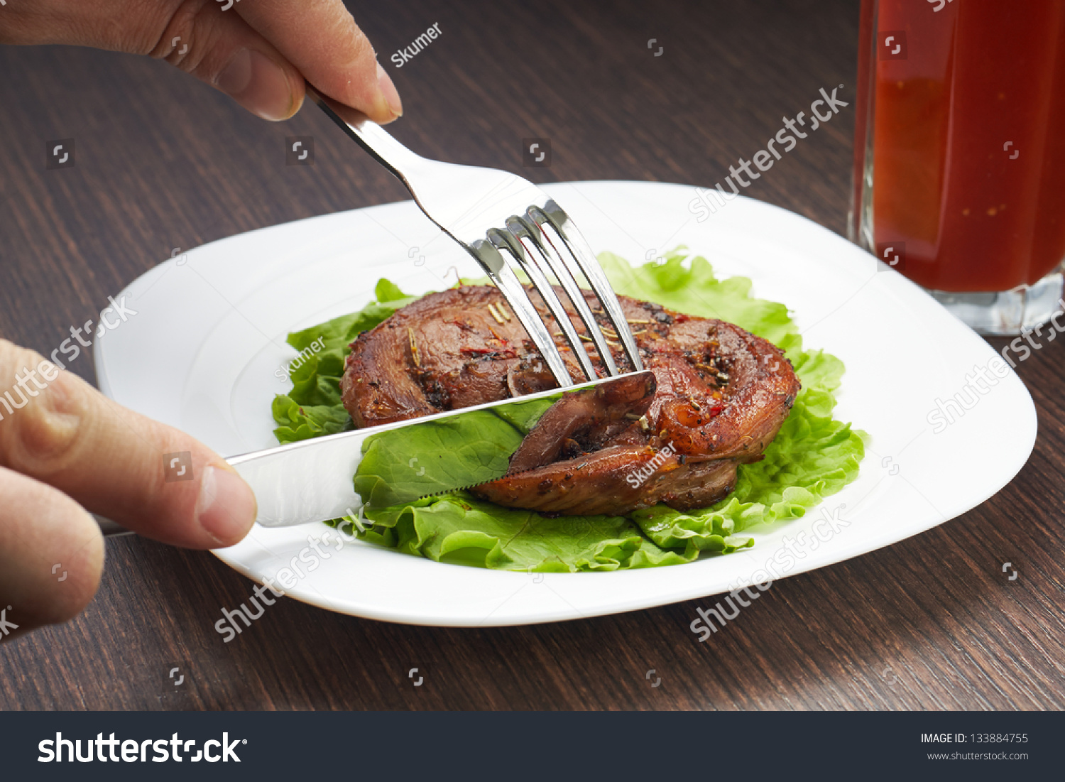 Cutting Grilled Steak With Knife And Fork On White Plate Stock Photo