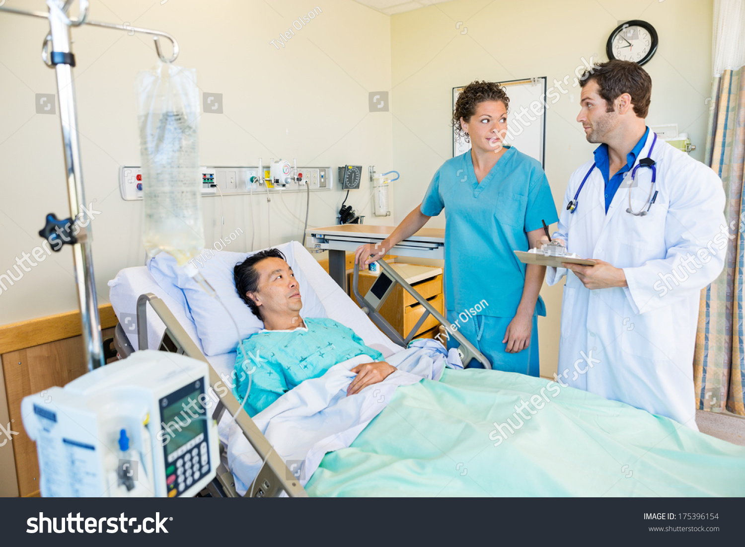 Doctor And Nurse Looking At Each Other While Patient Lying On Bed In