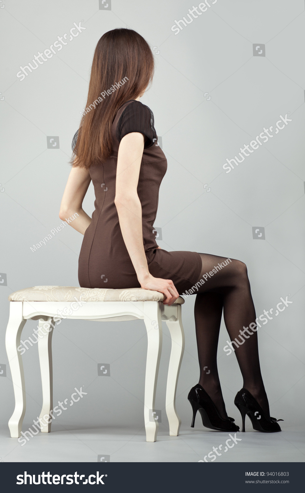 Elegant Long Haired Brunette Girl In Dress Sitting On A Chair Rear