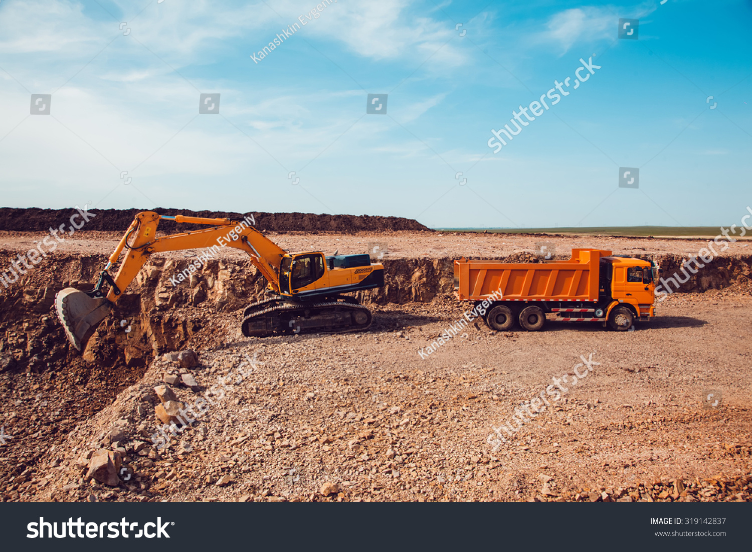 Excavator Loads Gravel into a Truck on a Crushed Stone Quarry Excavator Loads Gravel into a Truck on a Crushed Stone Quarry