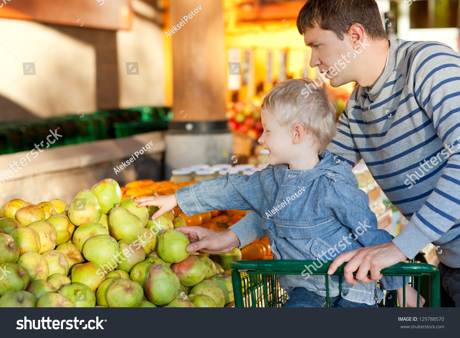 Father And His Cheerful Son Choosing Fruits At The Market Stock Photo