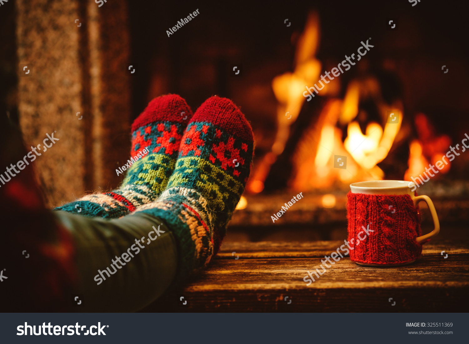Feet in woollen socks by the Christmas fireplace Woman relaxes by warm fire with a cup of hot drink and warming up her feet in woollen socks Close up on feet Winter and Christmas holidays concept Feet in woollen socks by the Christmas fireplace Woman relaxes by warm fire with a cup of hot drink and warming up her feet in woollen socks Close up on feet Winter and Christmas holidays concept
