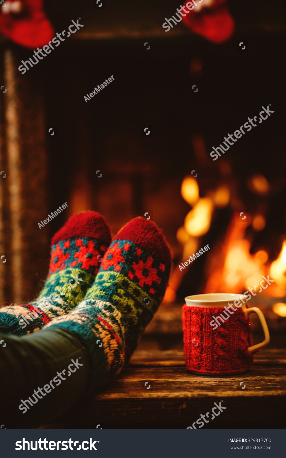 Feet in woollen socks by the Christmas fireplace Woman relaxes by warm fire with a cup of hot drink and warming up her feet in woollen socks Close up on feet Winter and Christmas holidays concept Feet in woollen socks by the Christmas fireplace Woman relaxes by warm fire with a cup of hot drink and warming up her feet in woollen socks Close up on feet Winter and Christmas holidays concept