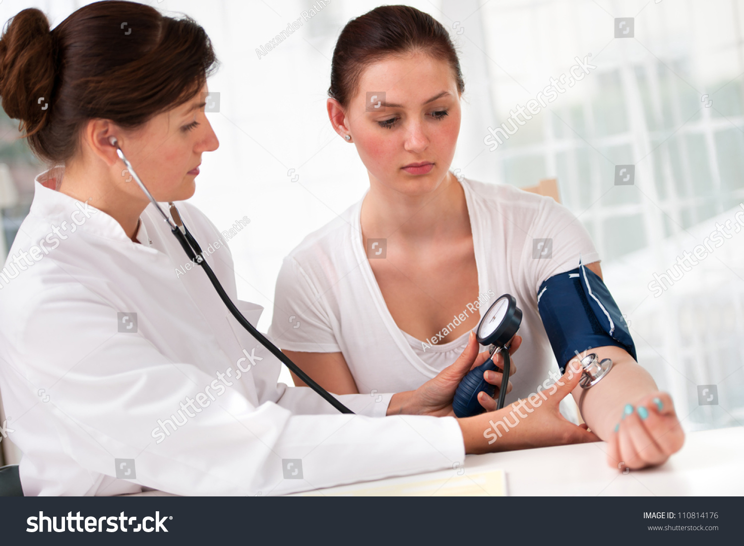 Woman having her blood pressure measured by doctor - Stock 