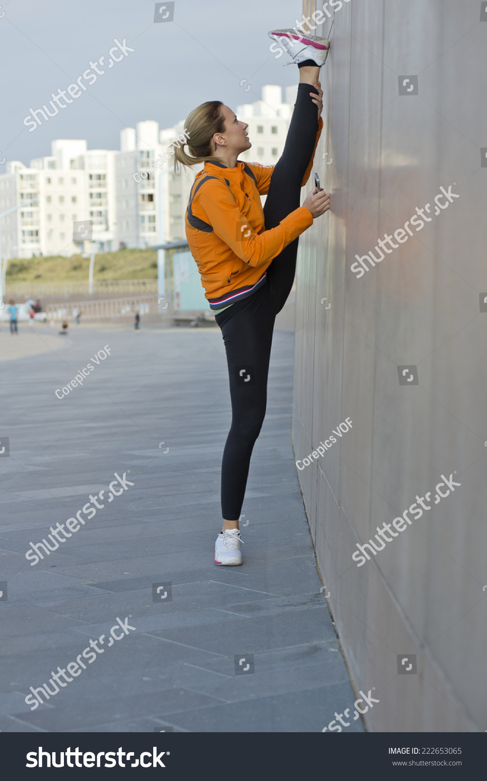 Flexible Female Athlete Stretching Her Legs In A Vertical Split Against