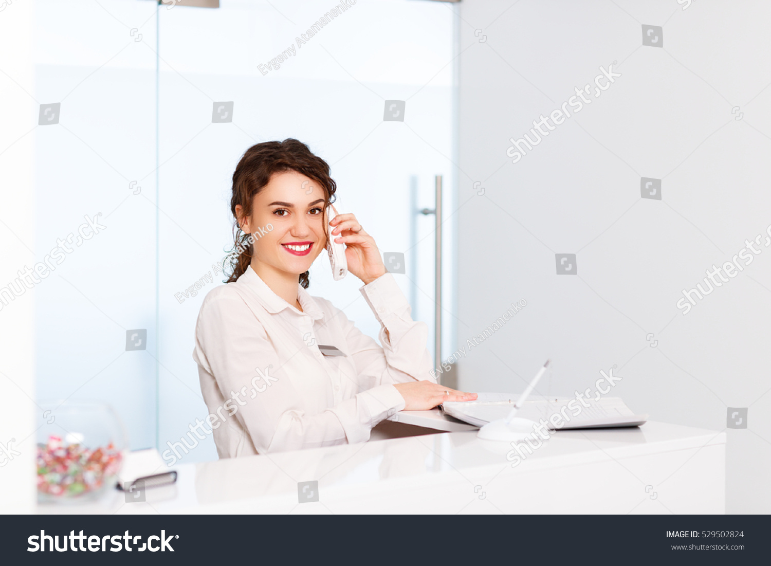 friendly young woman behind the reception desk administrator friendly young woman behind the reception desk administrator