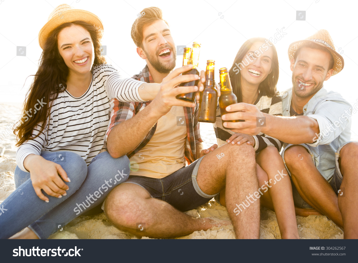 Friends having fun together at the beach and drinking a cold beer Friends having fun together at the beach and drinking a cold beer