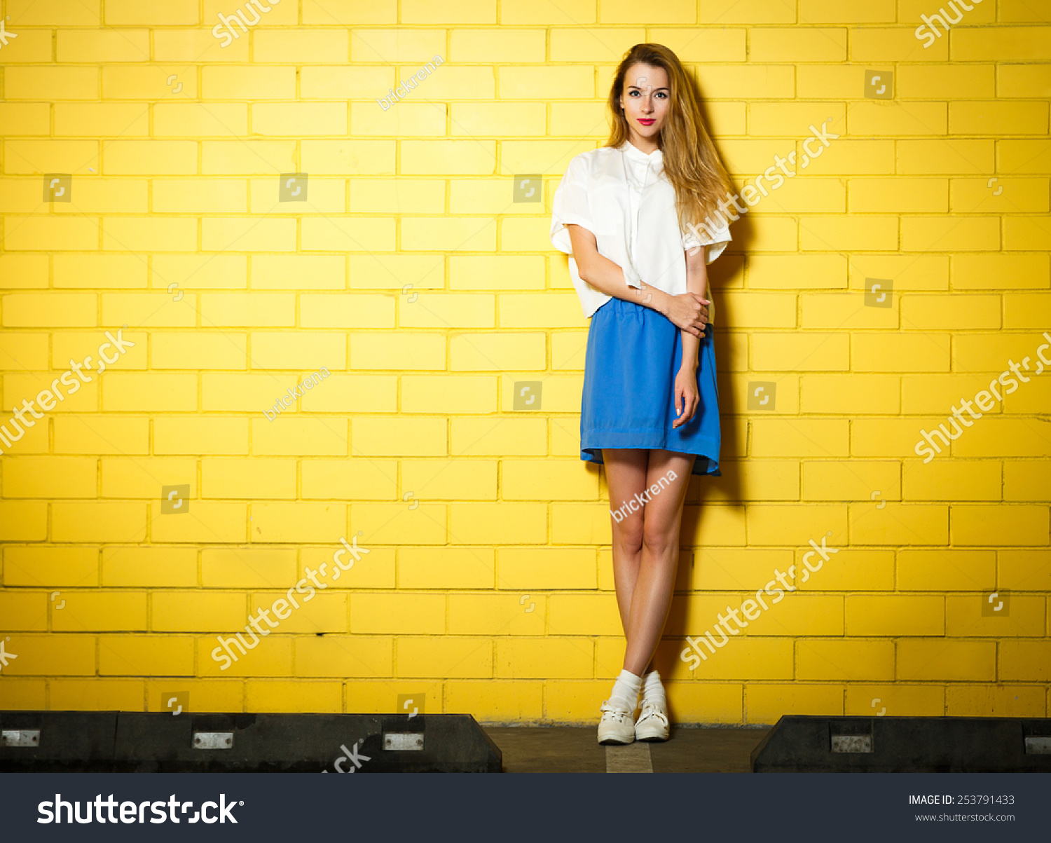 Full Length Portrait Of Trendy Hipster Girl Standing At The Yellow Brick Wall Background Urban