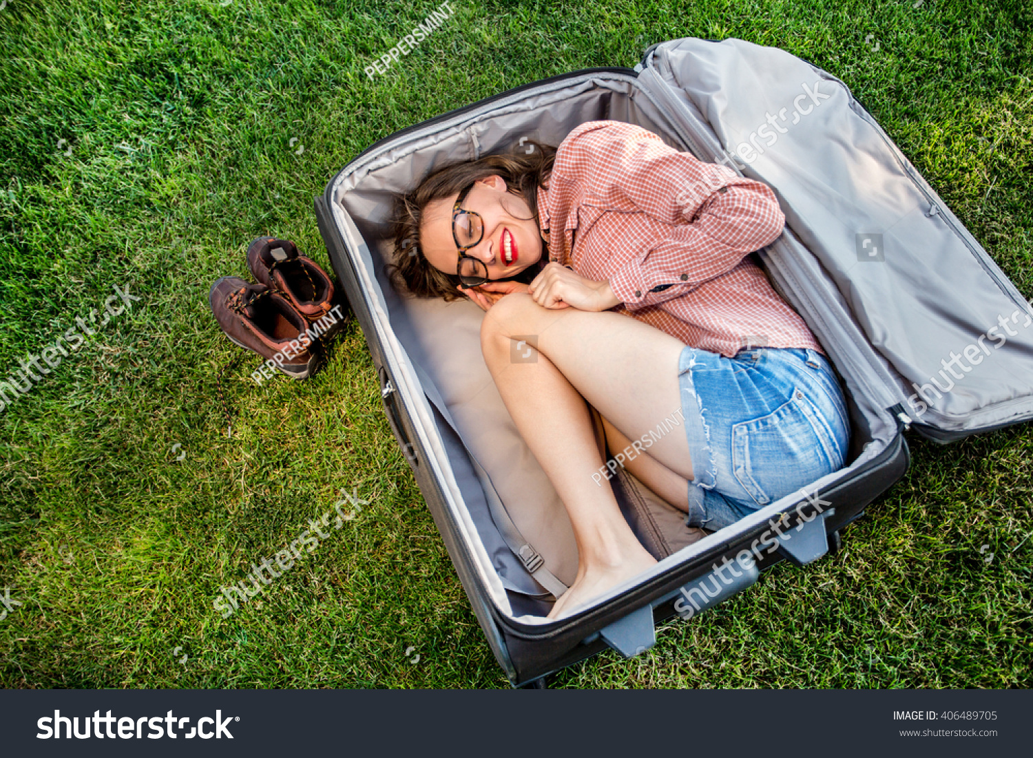 Funny traveler woman sitting in a huge suitcase and plan her trip Funny traveler woman sitting in a huge suitcase and plan her trip