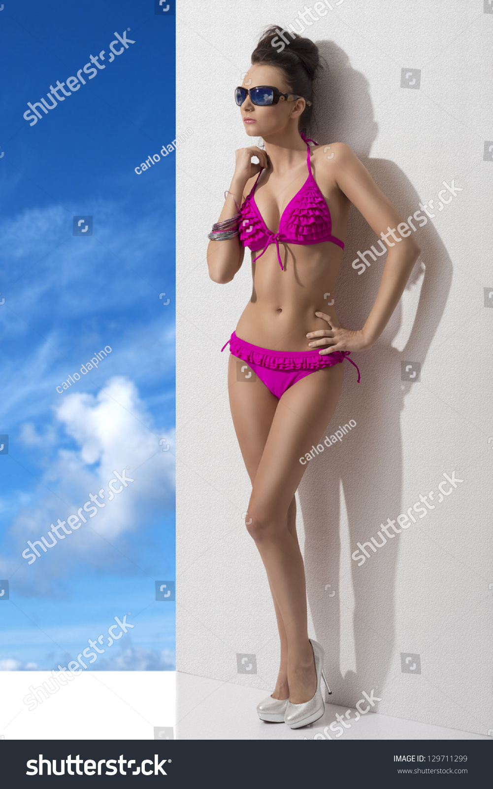 Girl Sexy Brunette With Pink Bikini And Sunglasses Against A White Wall