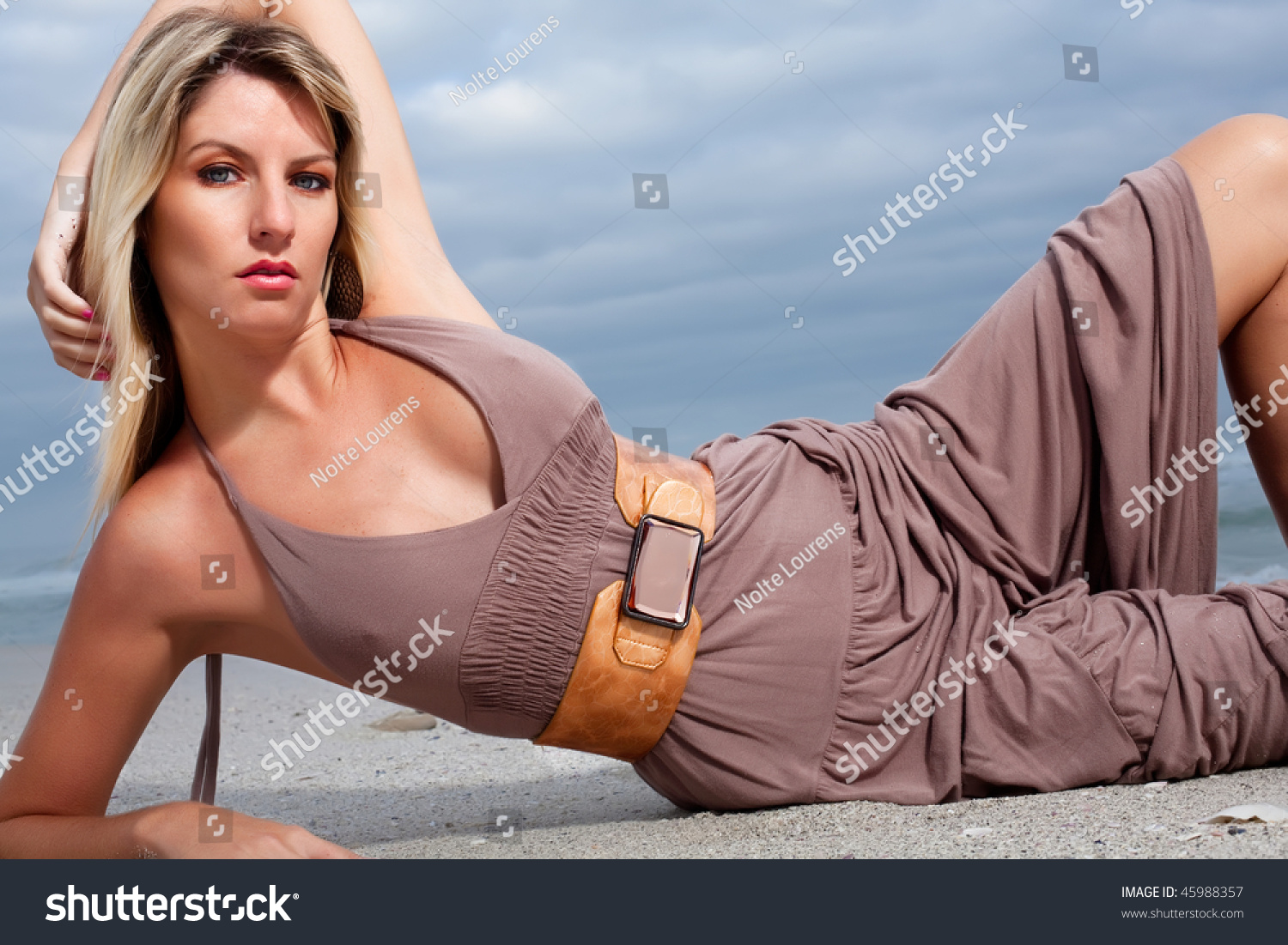 Good Looking Blond Woman Wearing A Brown Dress On The Beach Stock