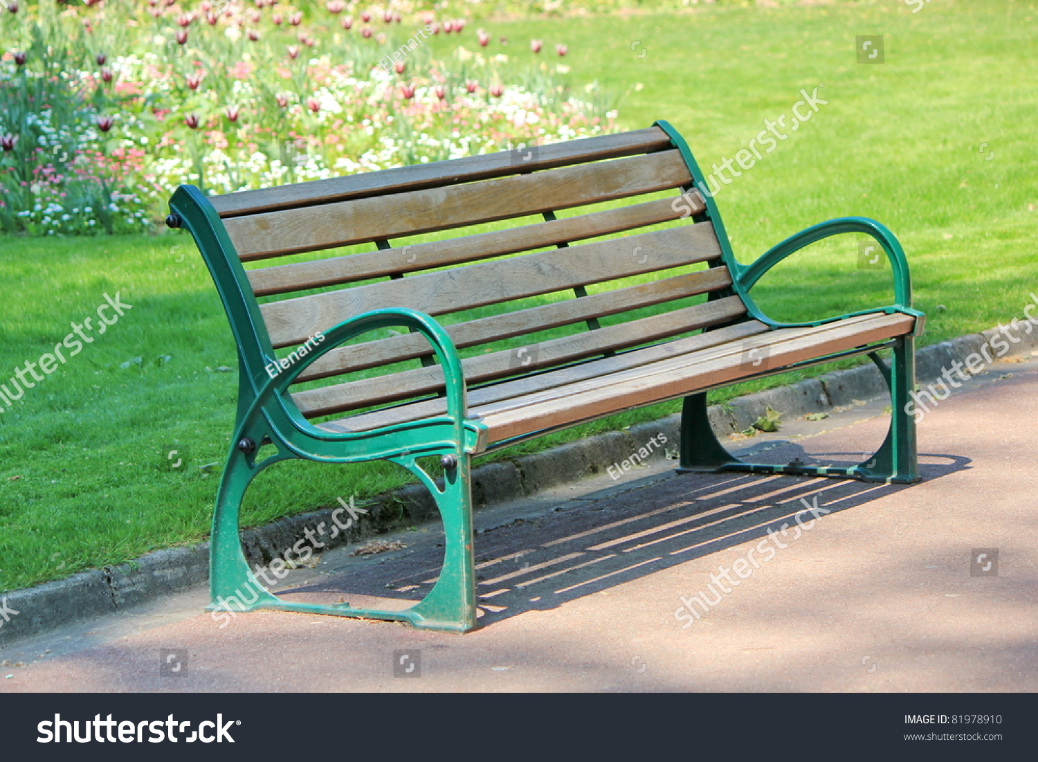 Green And Brown Wood Bench In A Park With Grass And Flowers Behind ...