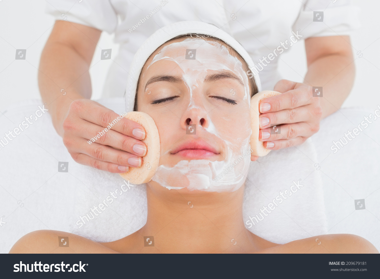 Hand cleaning woman's face with cotton swabs at spa center Hand cleaning woman's face with cotton swabs at spa center