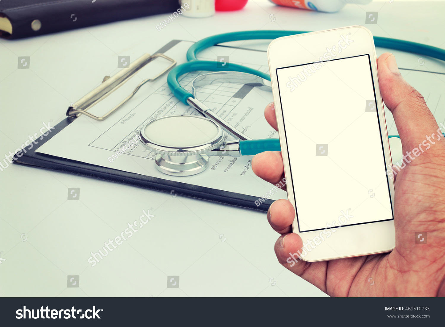 Hand holding mobile smart phone with blank screen in vertical position Medical stethoscope with clipboard and pen mockup template Hand holding mobile smart phone with blank screen in vertical position Medical stethoscope with clipboard and pen mockup template