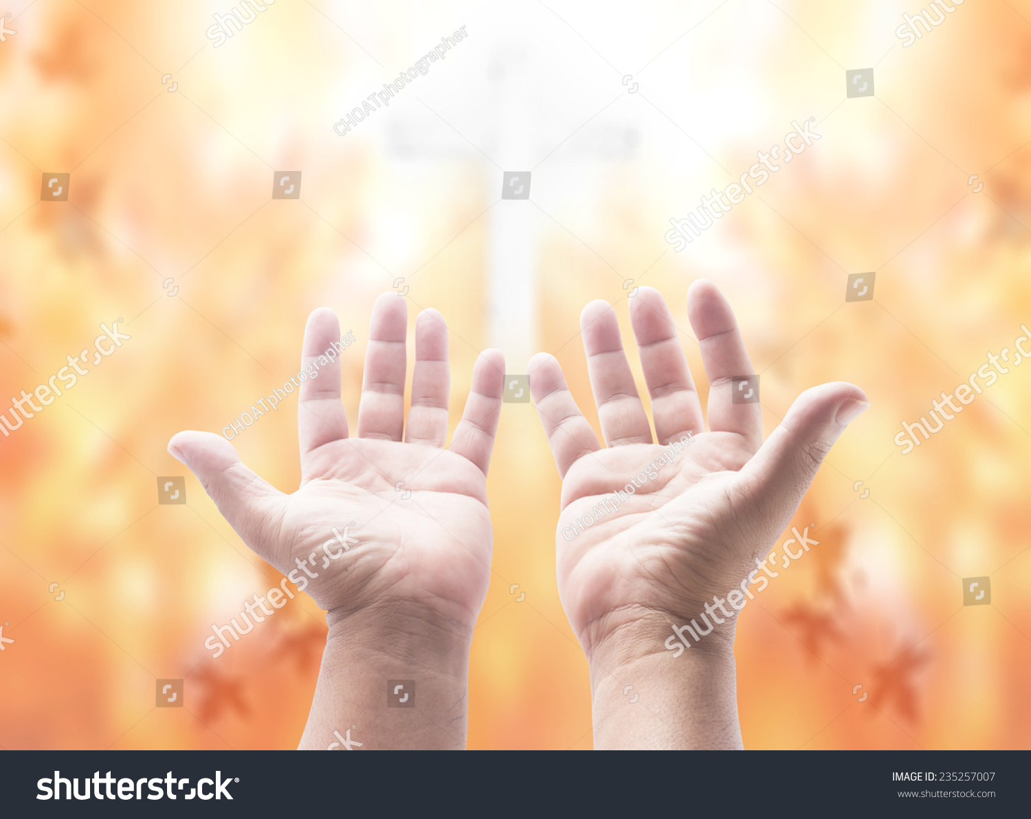 Hands Of Man Praying Over Blurred The Cross On Beautiful Autumn