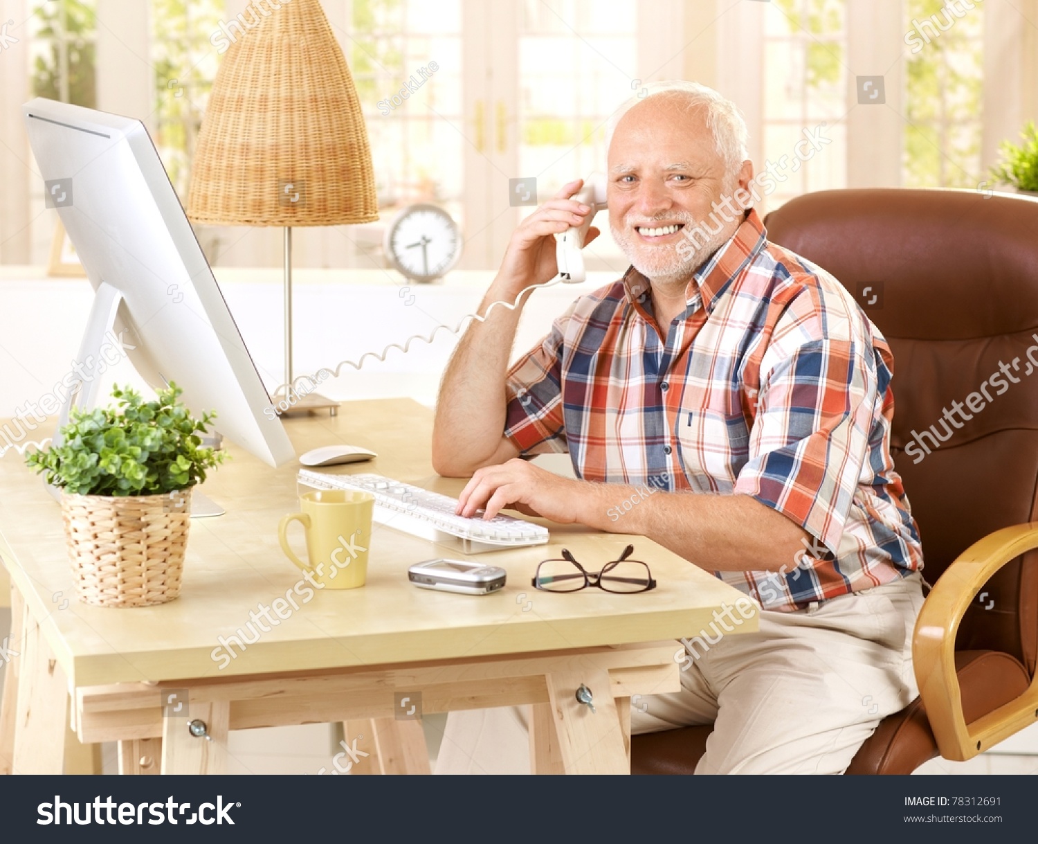 stock-photo-happy-old-man-on-landline-call-sitting-at-desk-using-computer-smiling-looking-at-camera-78312691.jpg