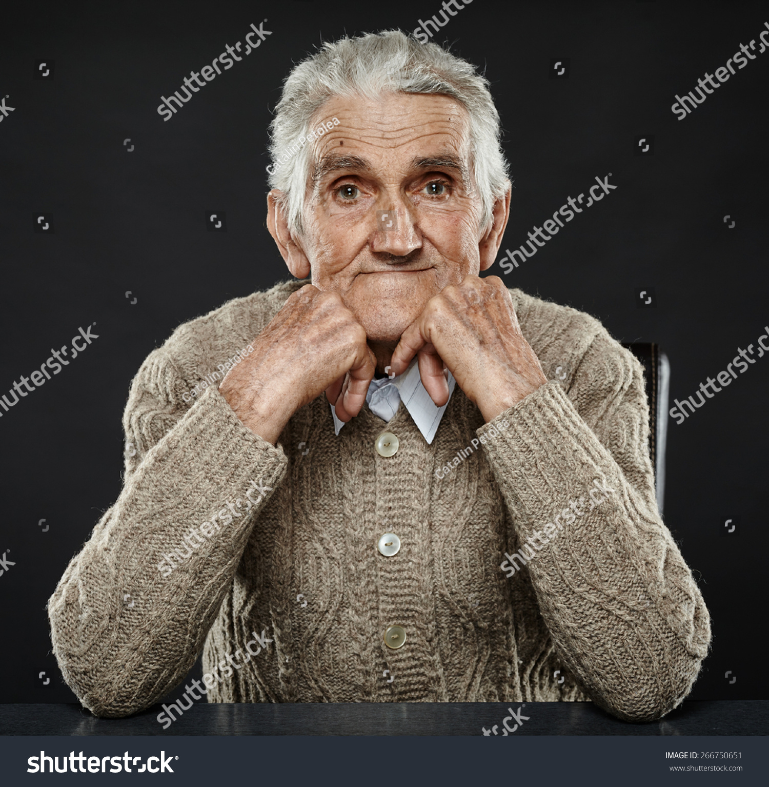 happy-80-years-old-man-sitting-at-the-desk-studio-shot-stock-photo