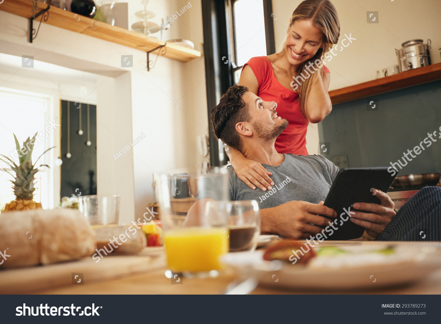 Happy Young Couple In Their Kitchen In Morning Man Sitting At