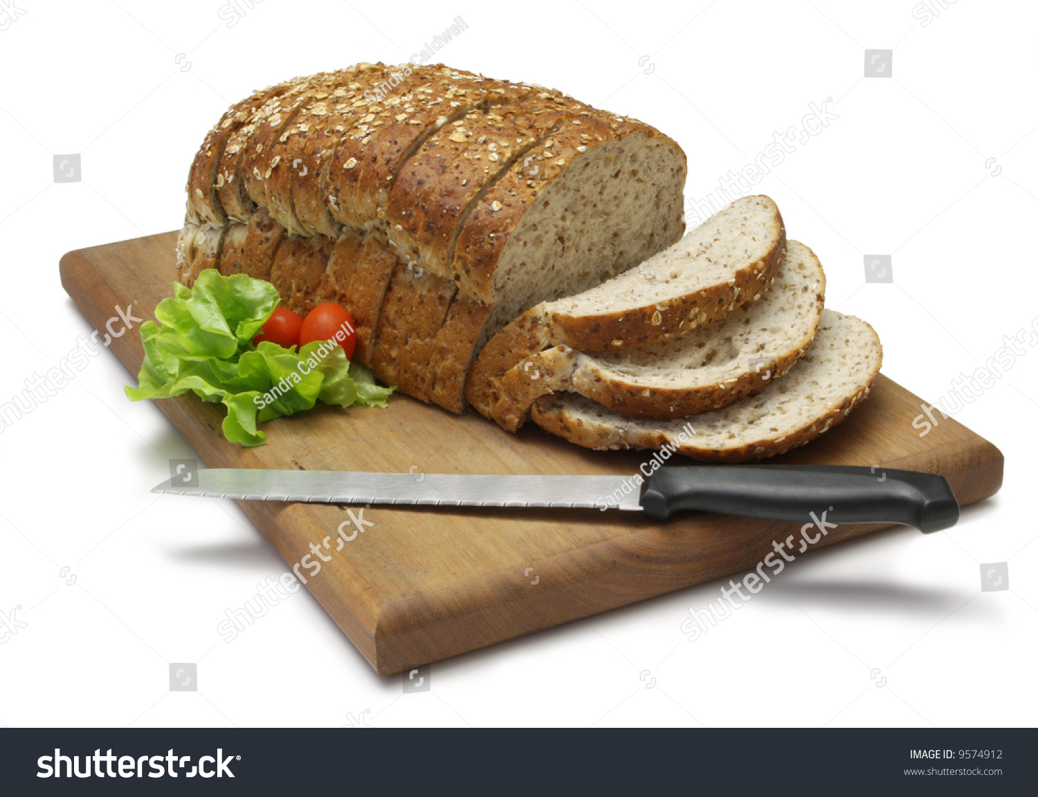 Loaf Of Sliced Whole Grain Bread On Wood Bread Board With Knife 