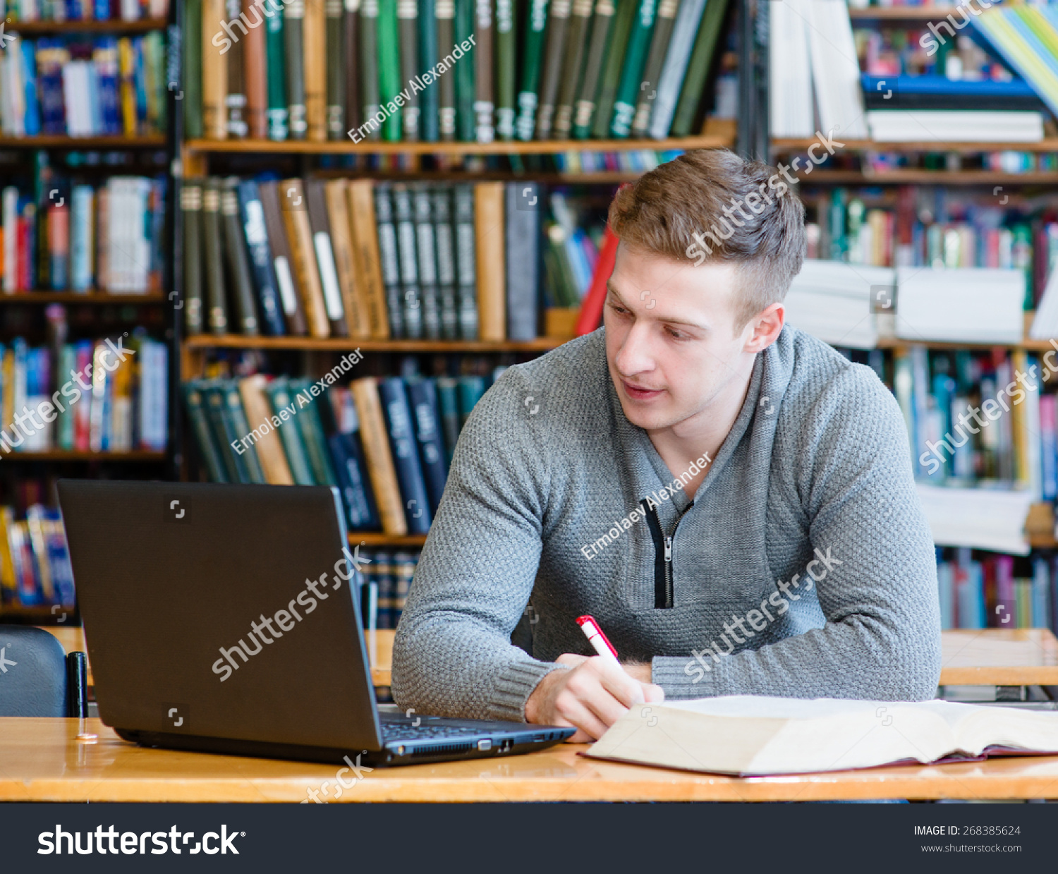 Male student with laptop studying in the university library Male student with laptop studying in the university library