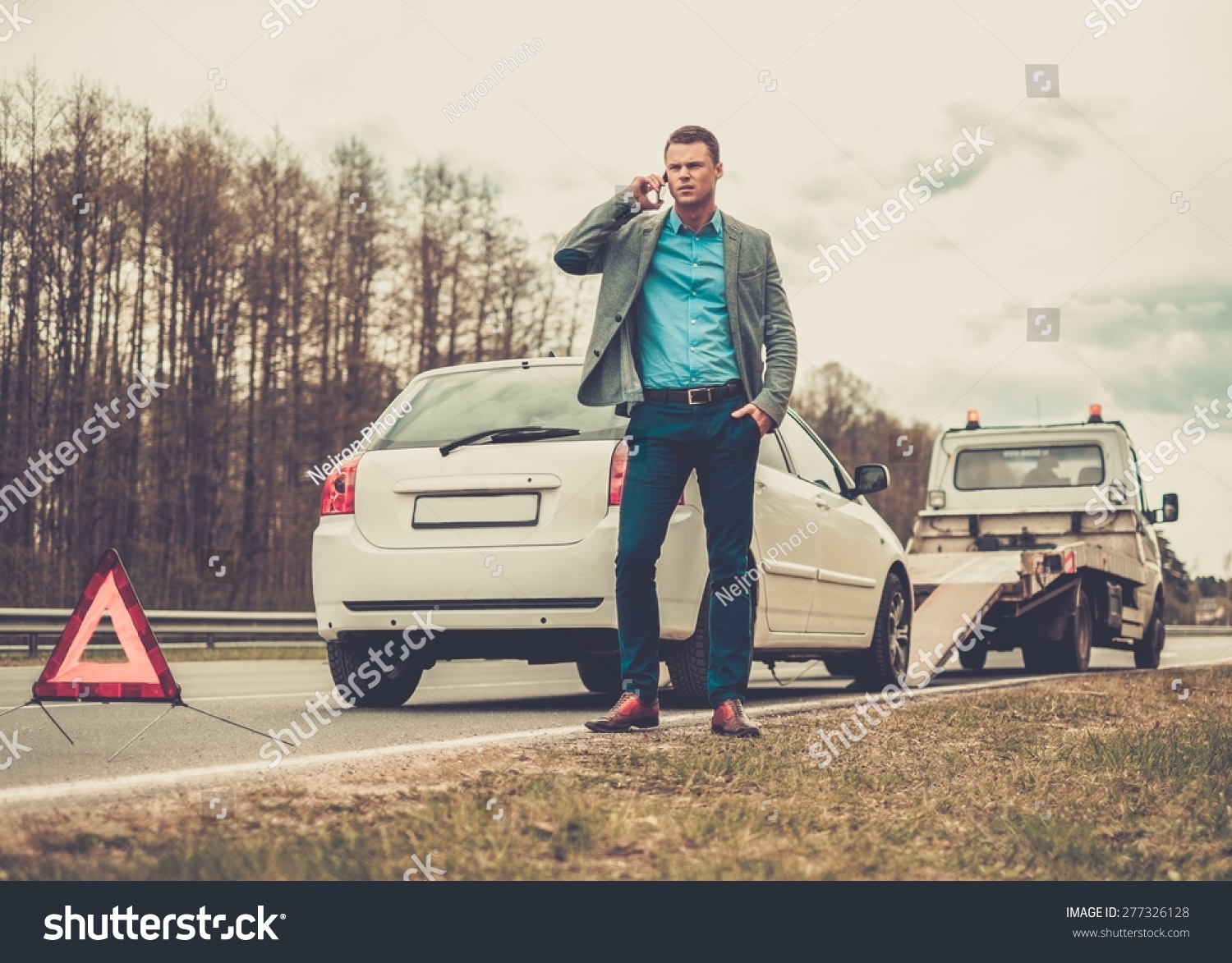 Man calling while tow truck picking up his broken car Man calling while tow truck picking up his broken car