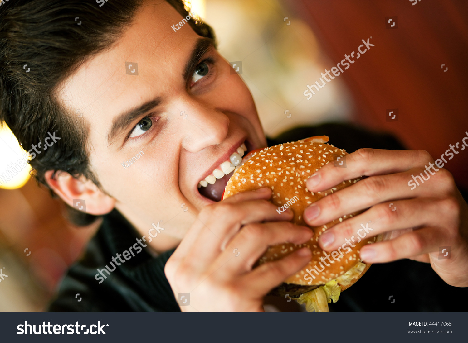 Man In A Restaurant Or Diner Eating A Hamburger He Is Hungry And