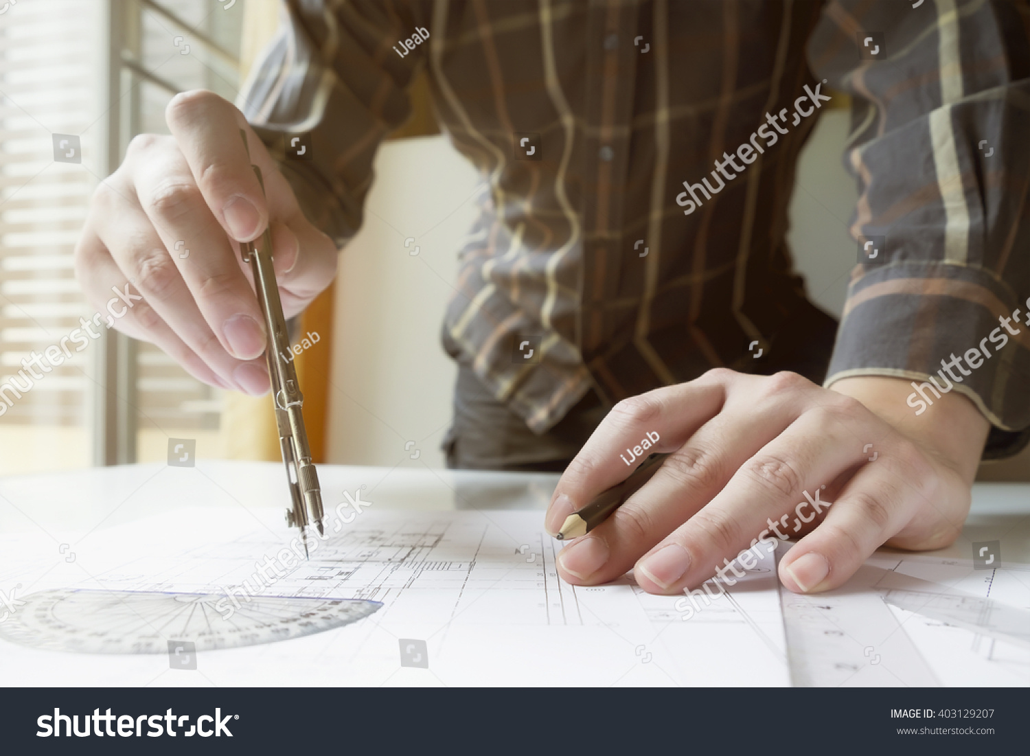 Man's hand with a compass Mechanical engineer at work Technical drawings Pencil compass calculator and hand man Paper with technical drawings and diagrams User sunlight vintage retro filter Man's hand with a compass Mechanical engineer at work Technical drawings Pencil compass calculator and hand man Paper with technical drawings and diagrams User sunlight vintage retro filter