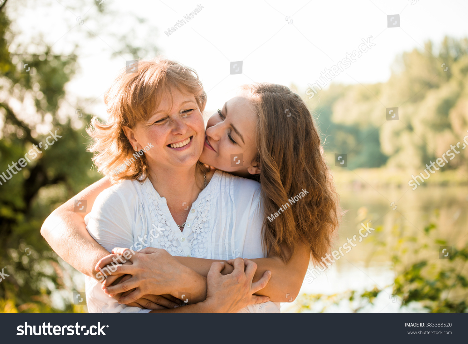 Mature Mother Hugging With Her Teen Daughter Outdoor In Nature On Sunny