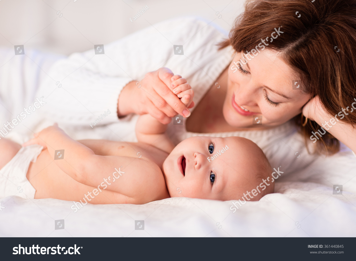 Mother and child on a white bed Mom and baby boy in diaper playing in sunny bedroom Parent and little kid relaxing at home Family having fun together Bedding and textile for infant nursery Mother and child on a white bed Mom and baby boy in diaper playing in sunny bedroom Parent and little kid relaxing at home Family having fun together Bedding and textile for infant nursery