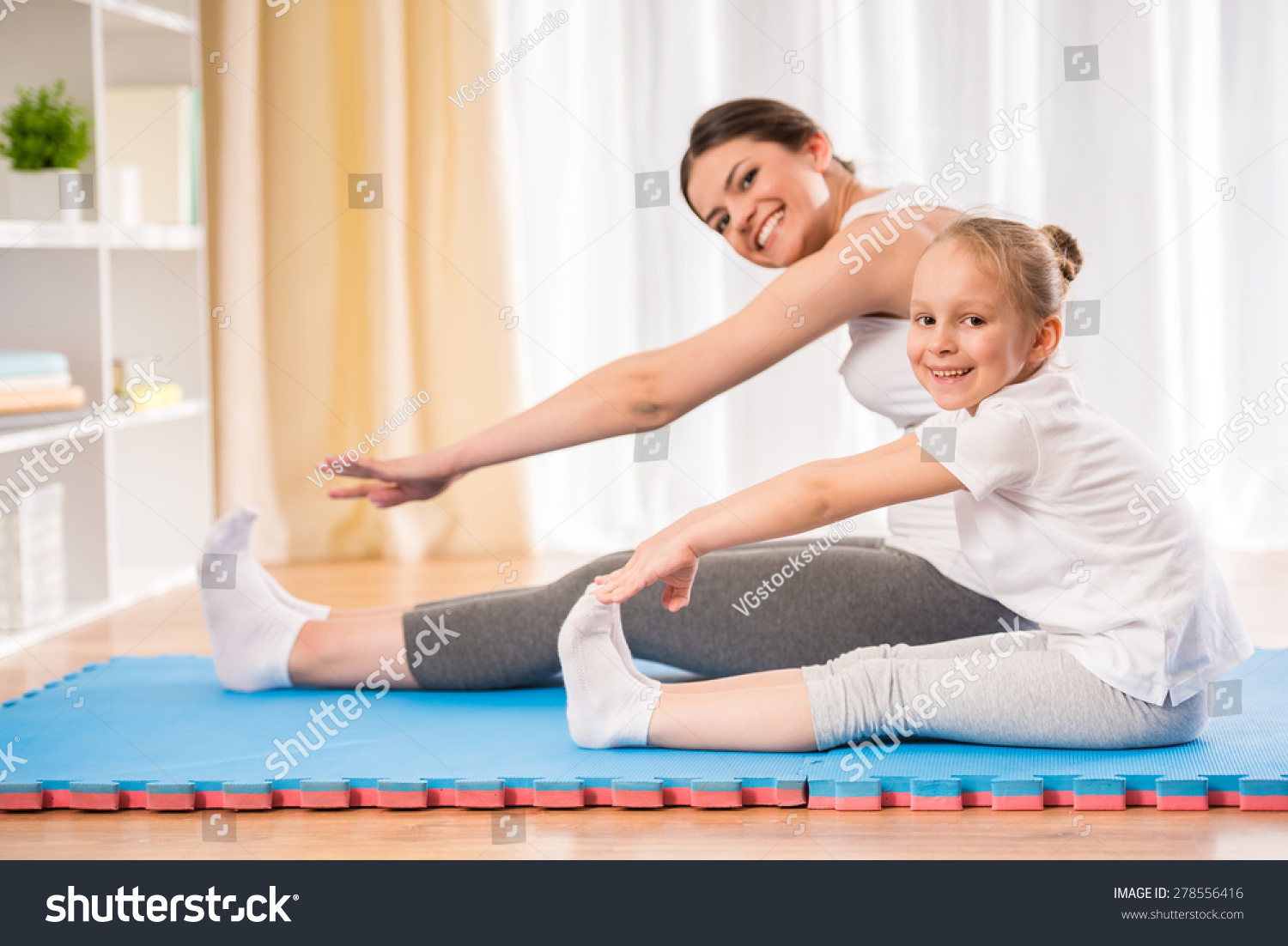 Mother Daughter Doing Yoga Exercises On Stock Photo