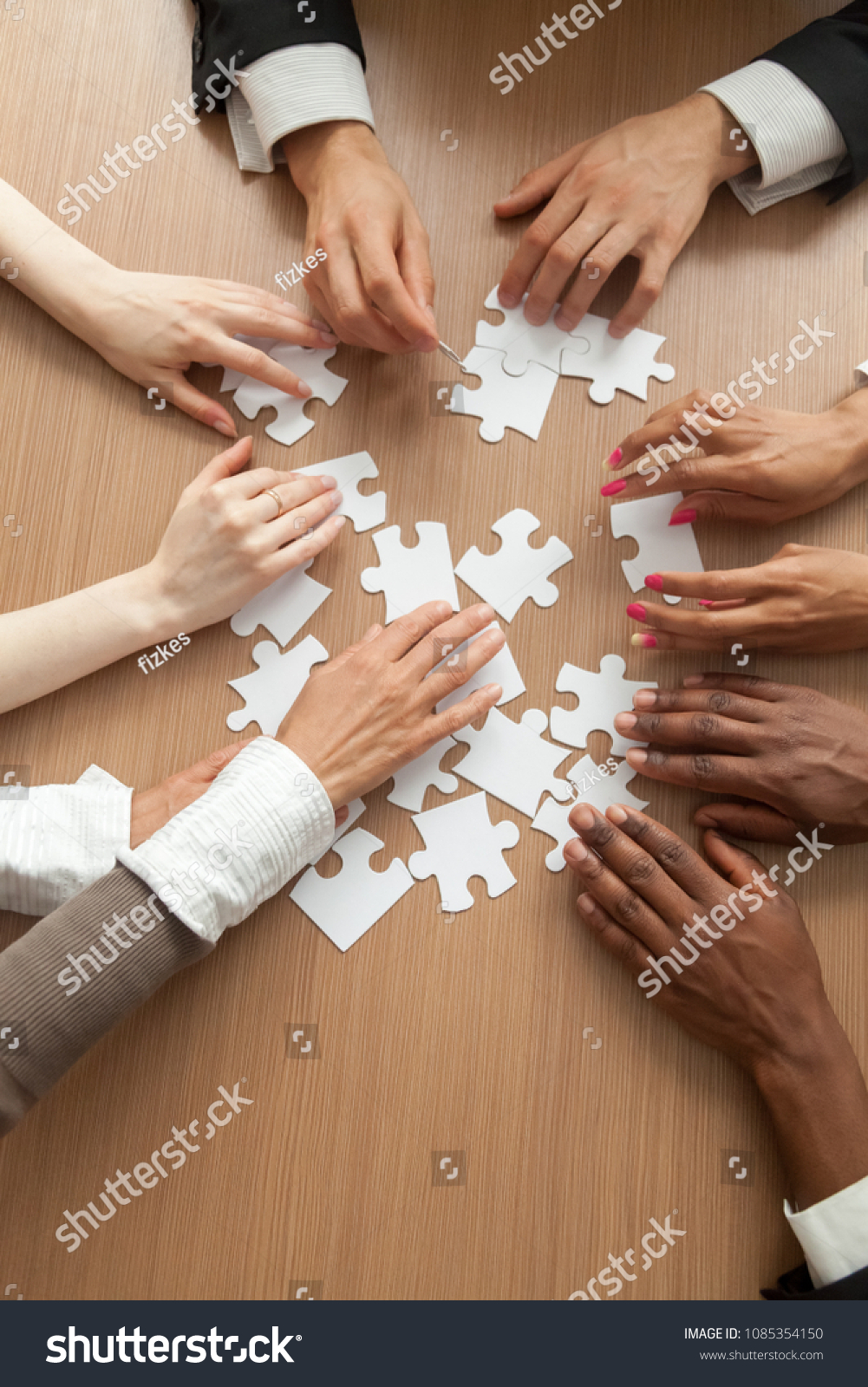 Multiracial Team Assembling Puzzle Together Hands Stock Photo