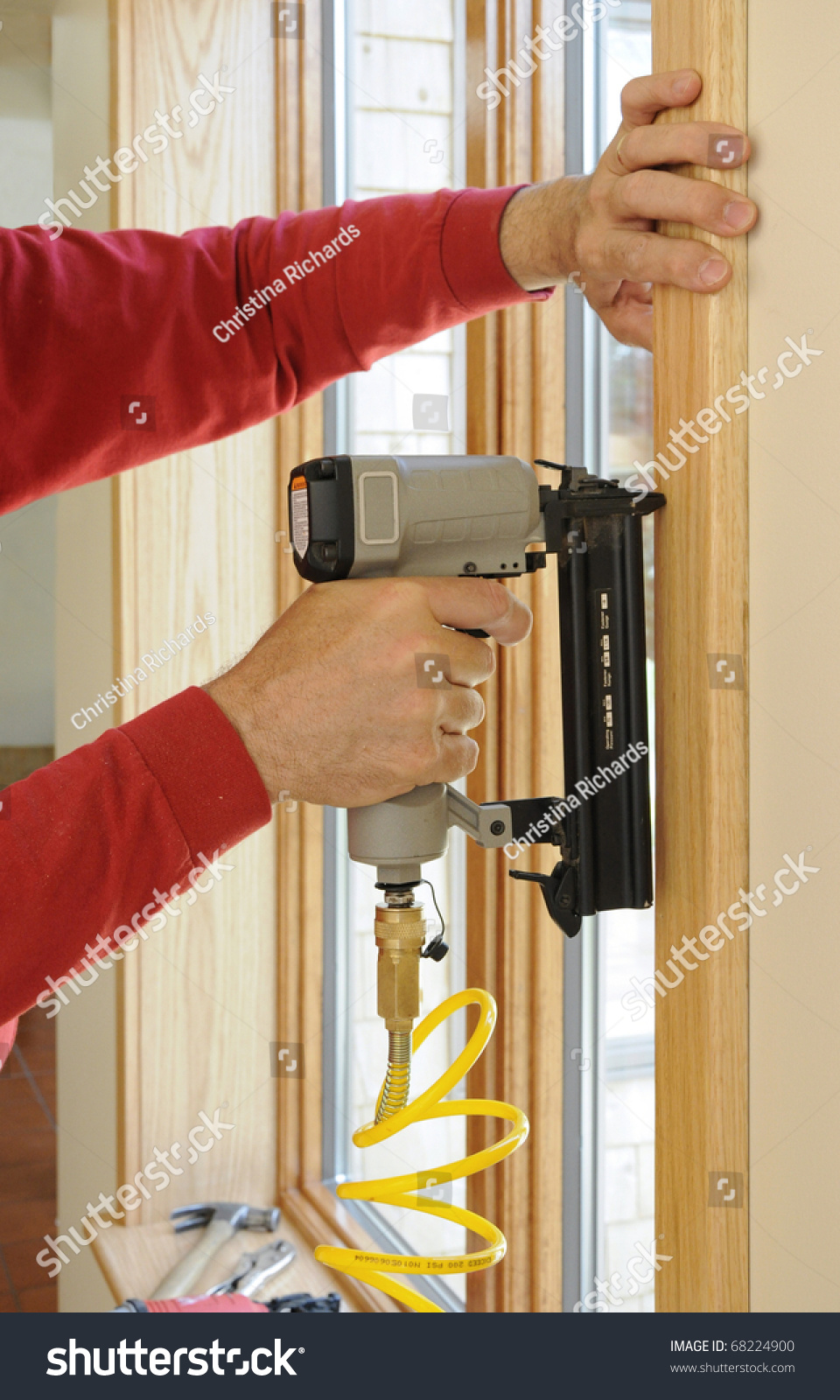 Nail Gun Being Used To Install Wood Trim Around Windows With Finishing