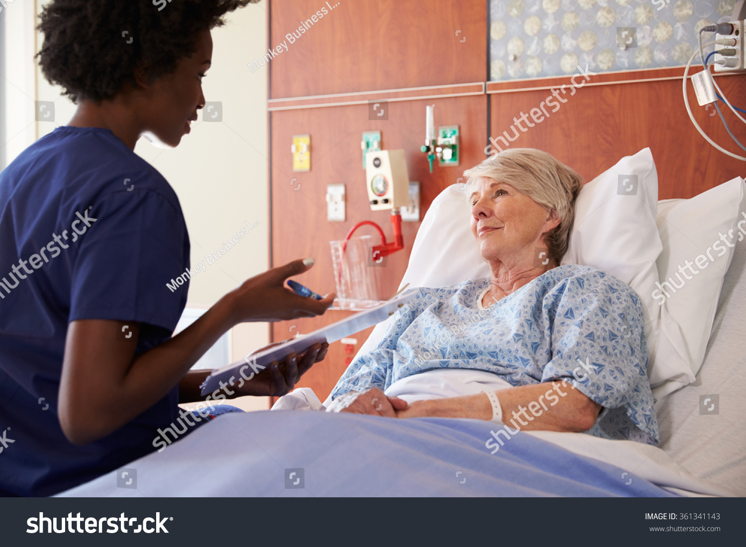 Nurse Talking To Senior Female Patient In Hospital Bed 