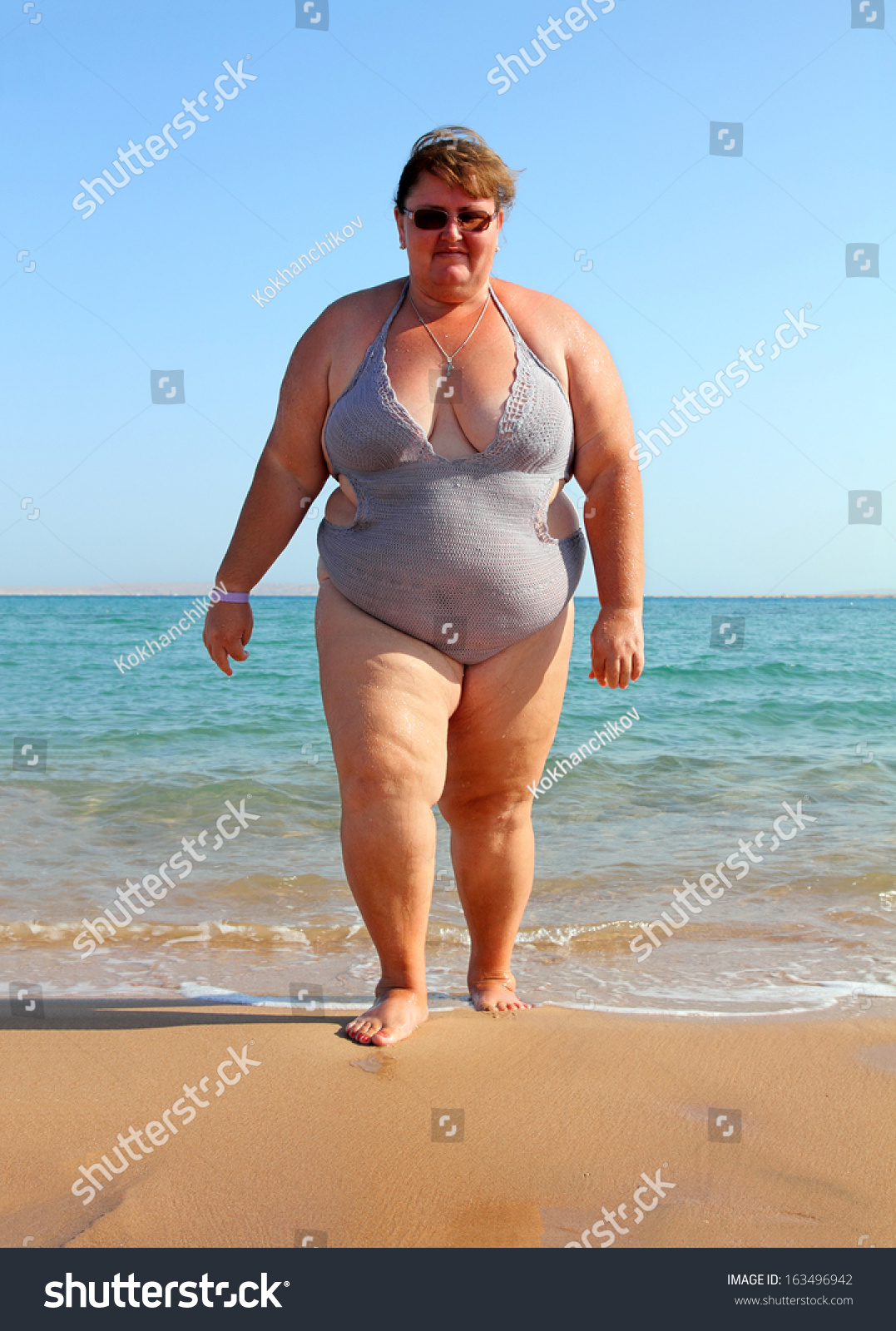 Overweight Woman Walking On Beach Near Sea Stock Photo