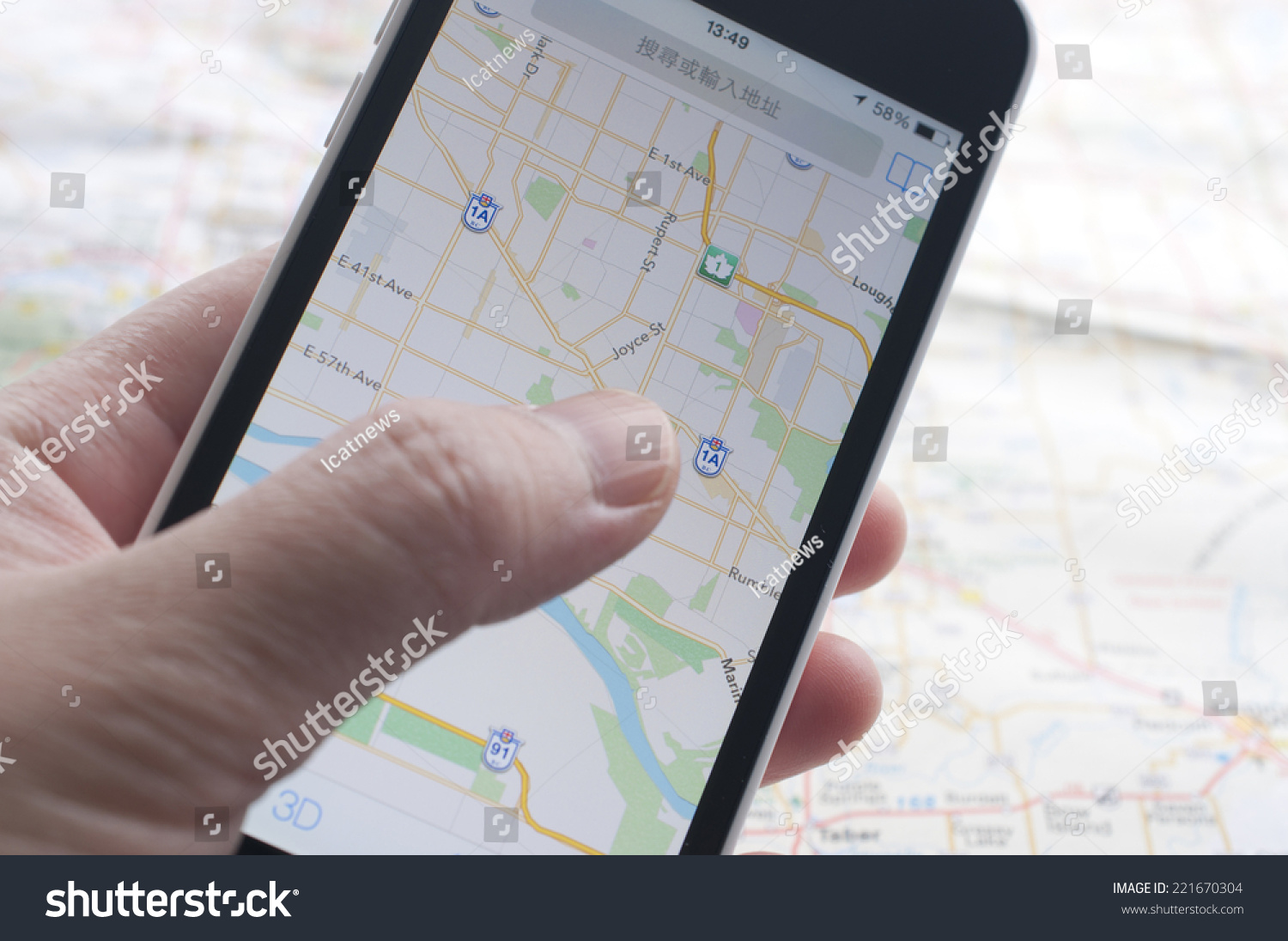  A person is holding a smartphone and checking the GPS coordinates while using a map for directions.