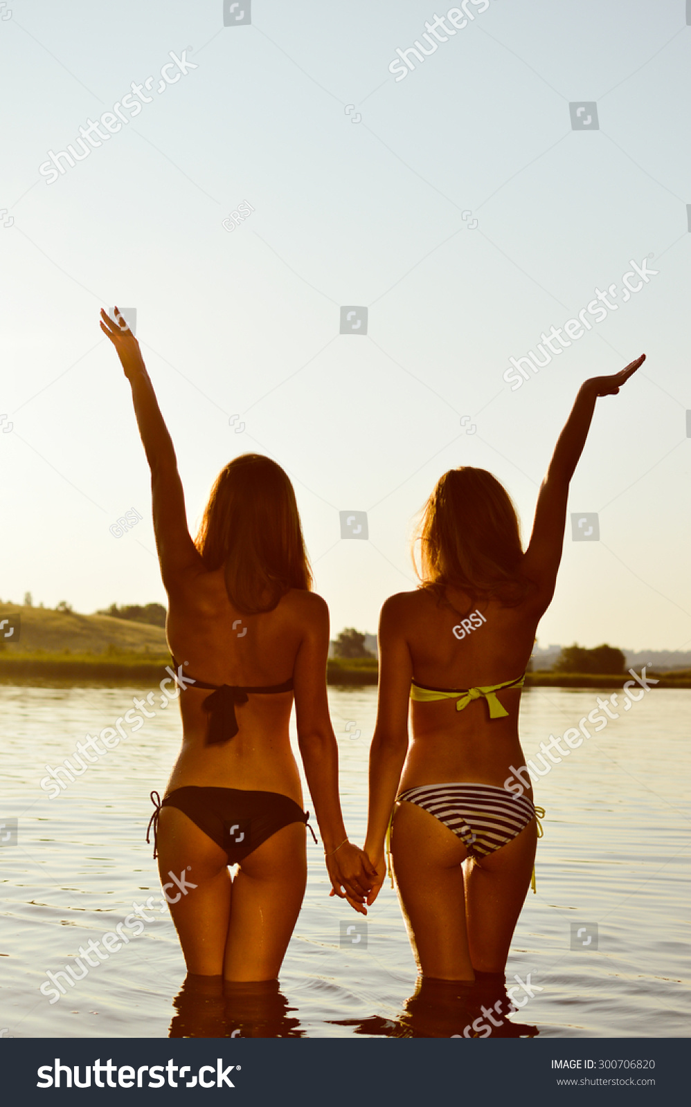 Picture Of Two Sexy Best Girlfriends In Bikini Having Fun Together Holding Hands Up To Sky On