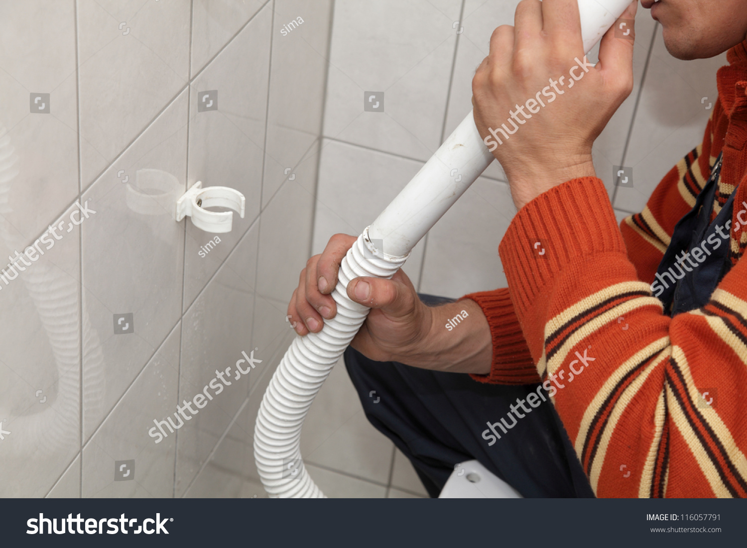 Plumber Fixing Plastic Tube Of Wall Mounted Toilet Cistern Stock Photo