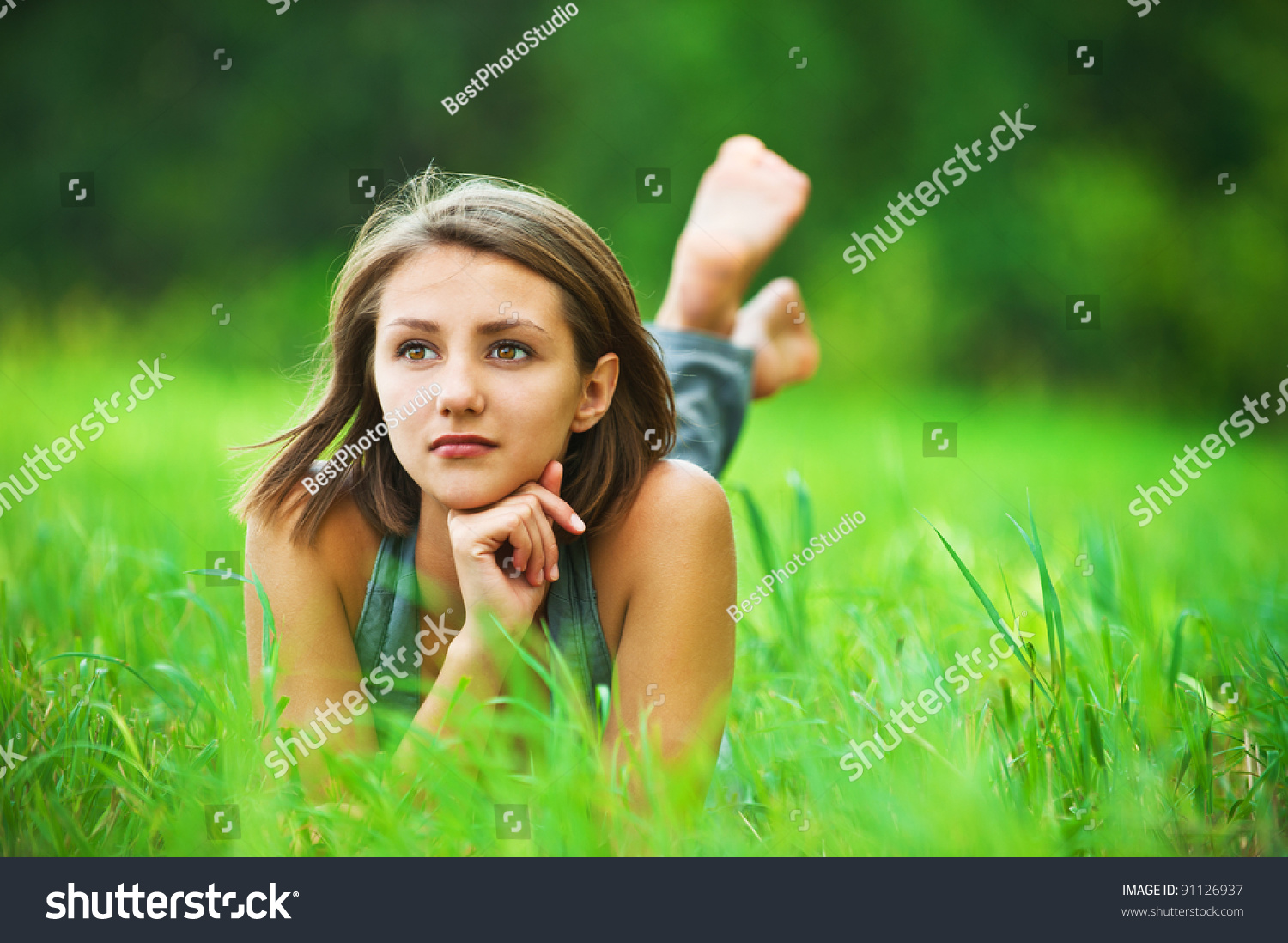 Portrait Of Romantic Young Woman With Short Hair Lying On Green Grass 